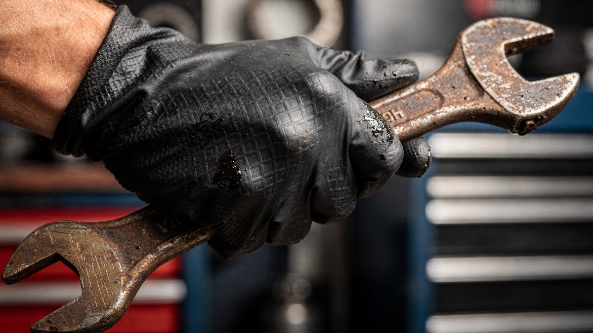 8 mil diamond textured black nitrile glove gripping a wrench